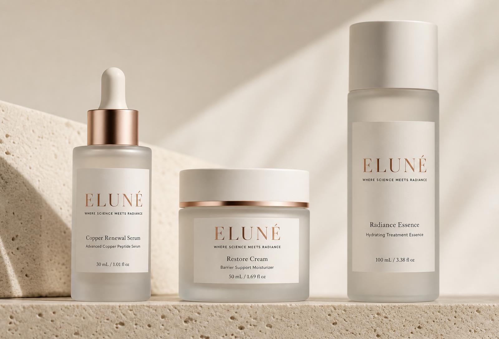 ELUNÉ frosted glass skincare bottles on travertine in soft natural light